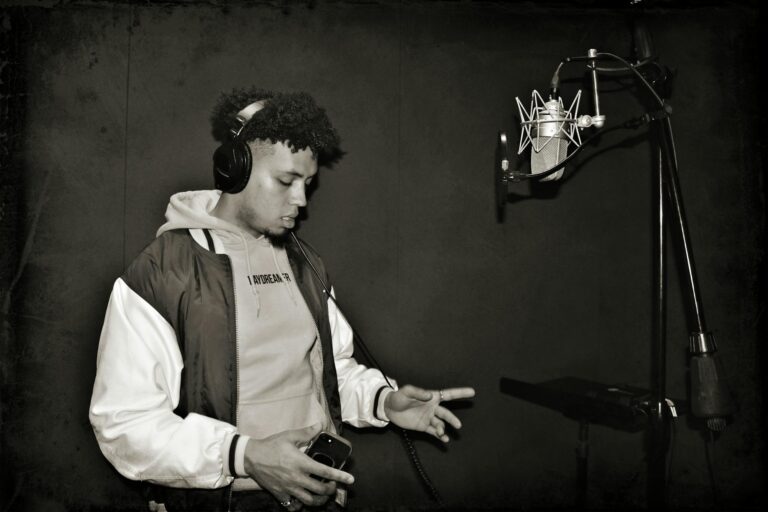 A focused young rapper performing in a professional recording studio.